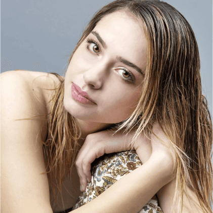 Ritratto di una giovane donna con capelli bagnati, che posa con un'espressione serena e uno sfondo neutro.