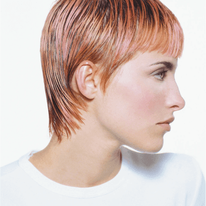 Modello con capelli corti e bagnati di colore rosa, visibile di profilo, indossa una maglietta bianca.