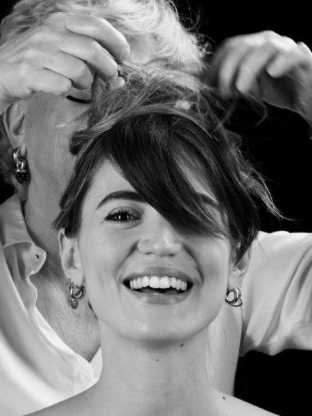 Donna sorridente con capelli acconciati da un parrucchiere, mostrando un'acconciatura elaborata e dettagliata.